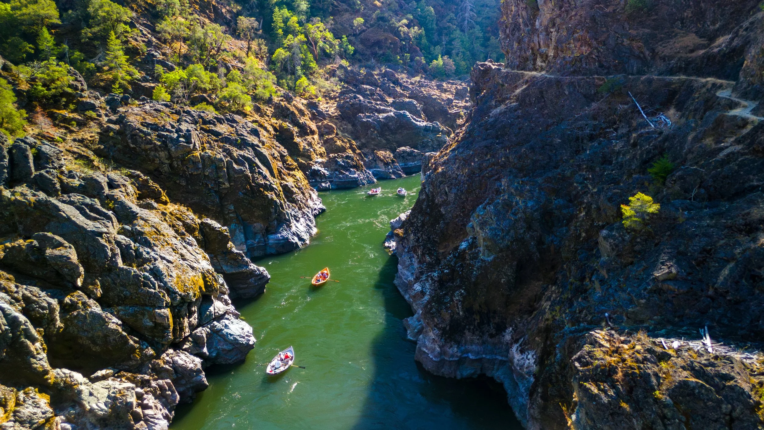 Aerial drone photo of drift boats floating through a canyon on the Rogue River in southern Oregon.