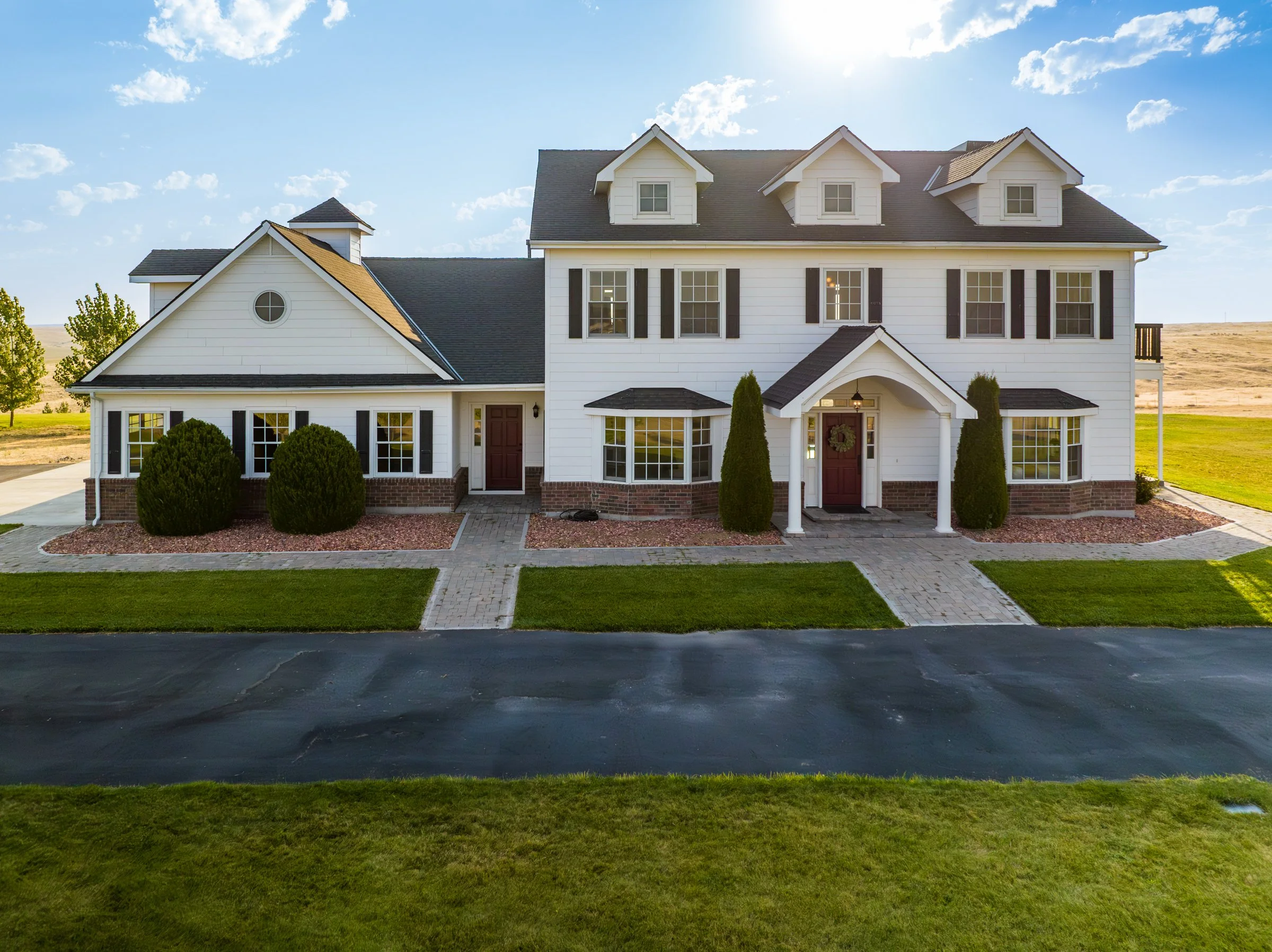 Aerial drone photo of the front exterior of a luxury home in Idaho, showing driveway, landscaping, and architectural design.