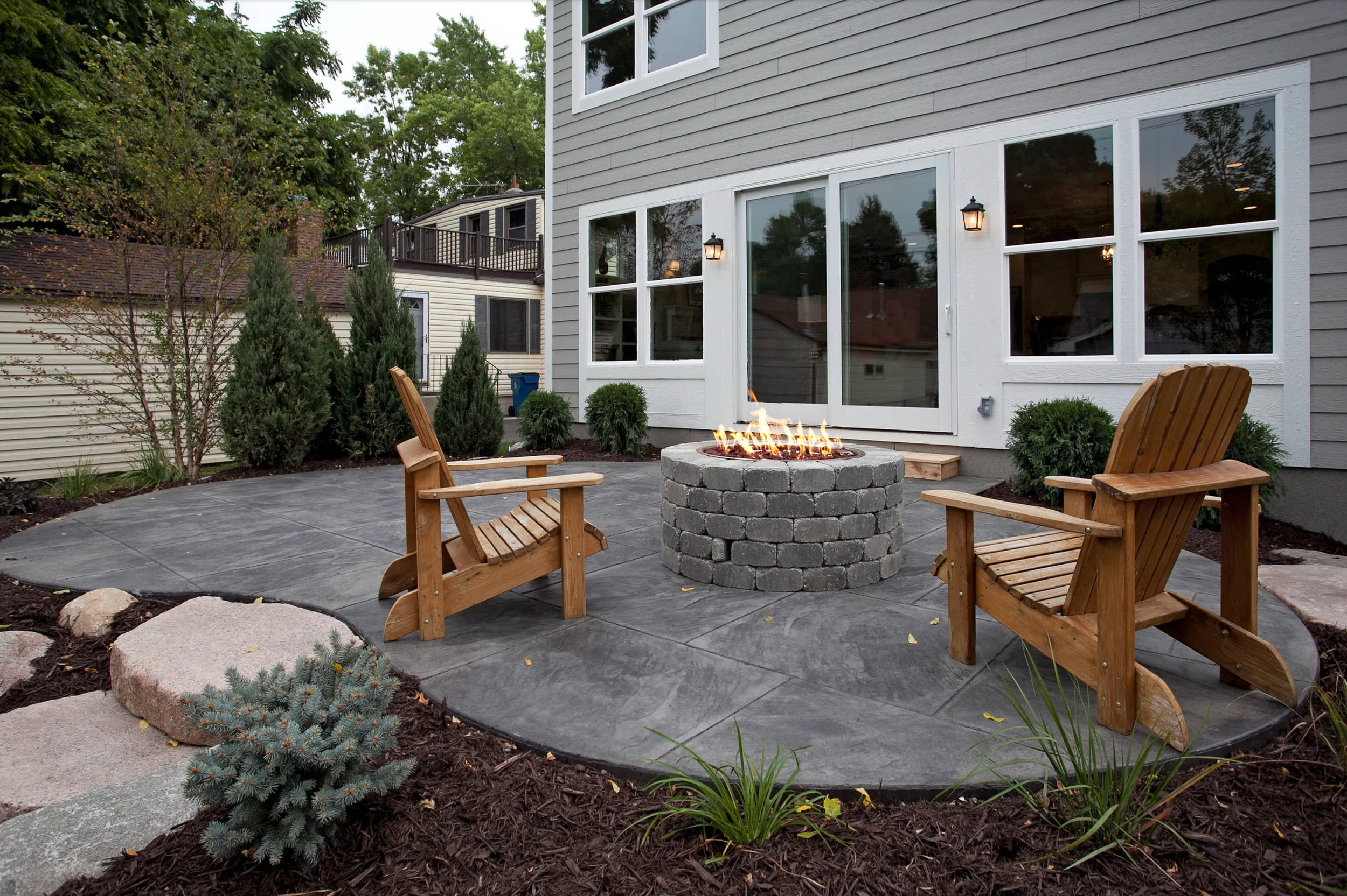 Stamped concrete patio surrounding a backyard fire pit.