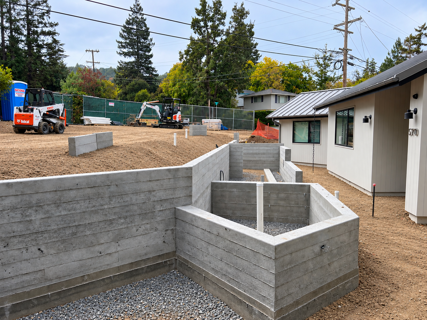 Board-formed concrete walls defining planting areas during construction.