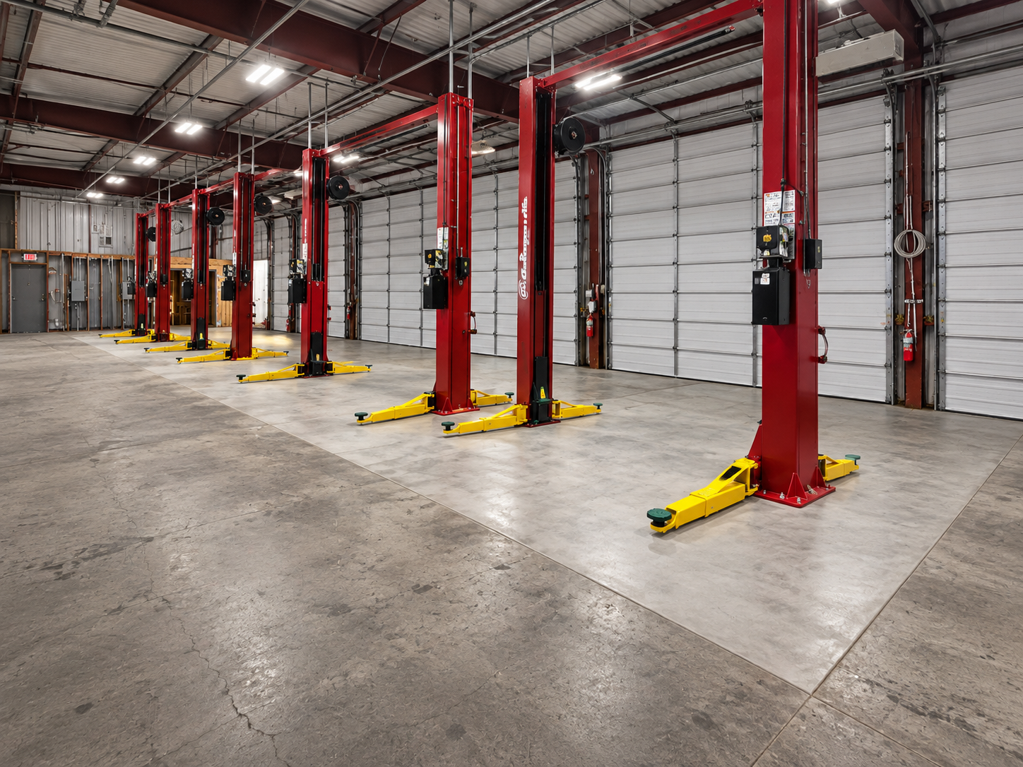 Completed concrete foundations supporting vehicle lifts at a Tesla service facility.