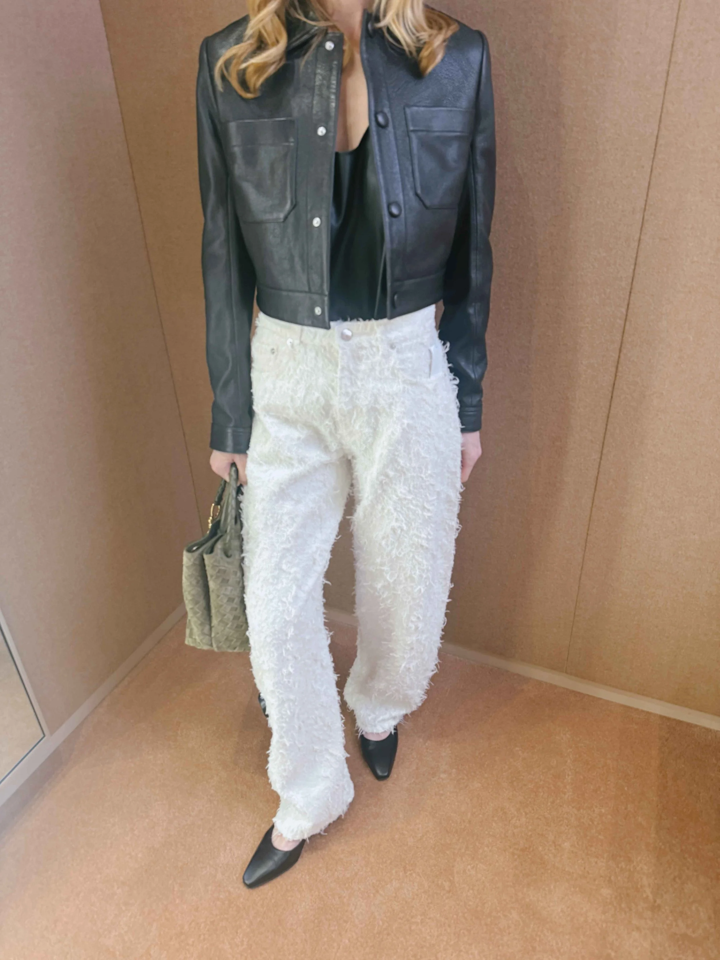Woman wearing a trendy white feathered jean with cropped leather jacket. Easy wardrobe stapes for day to night.