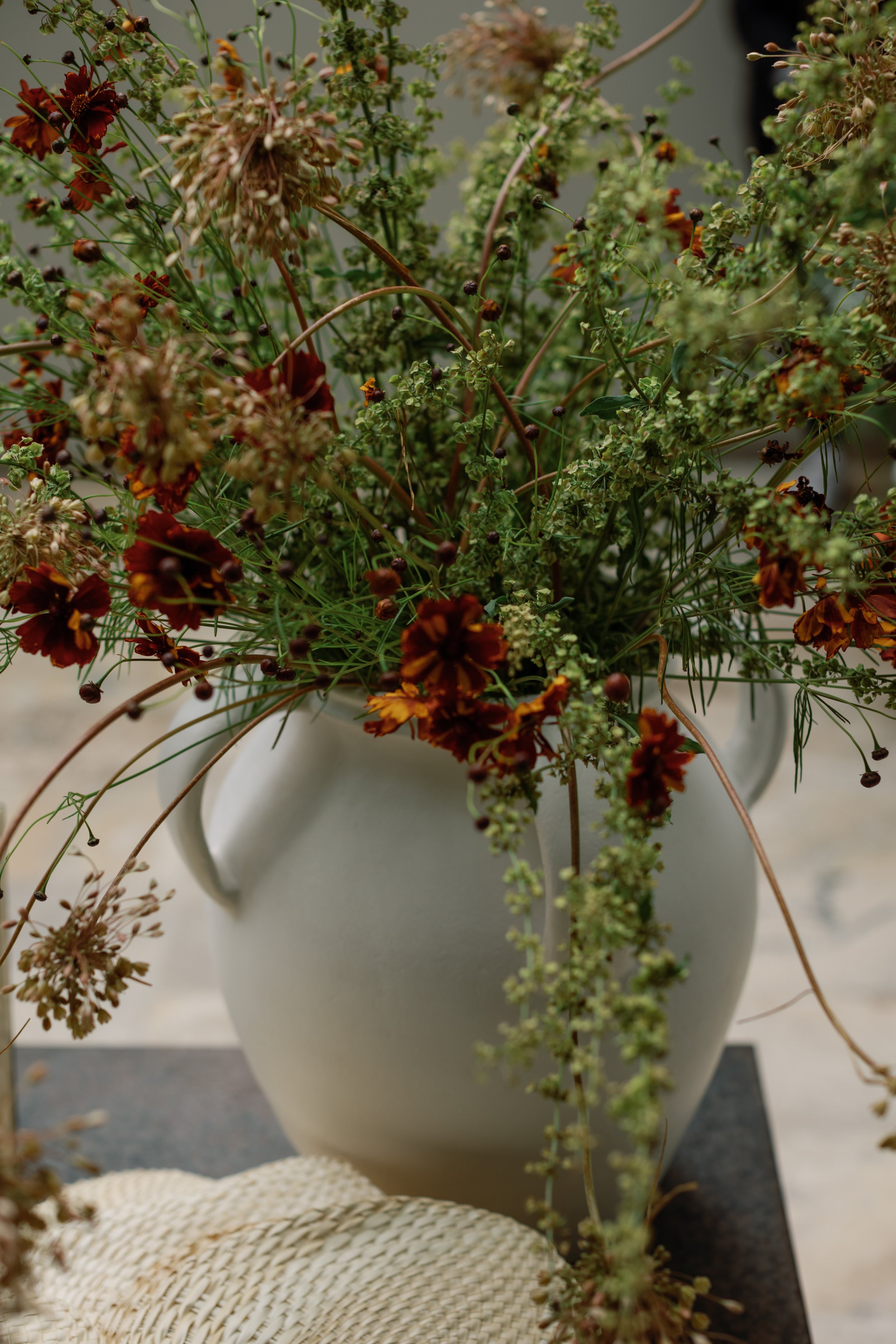  Red and orange flowers mixed with greenery in a white pot 