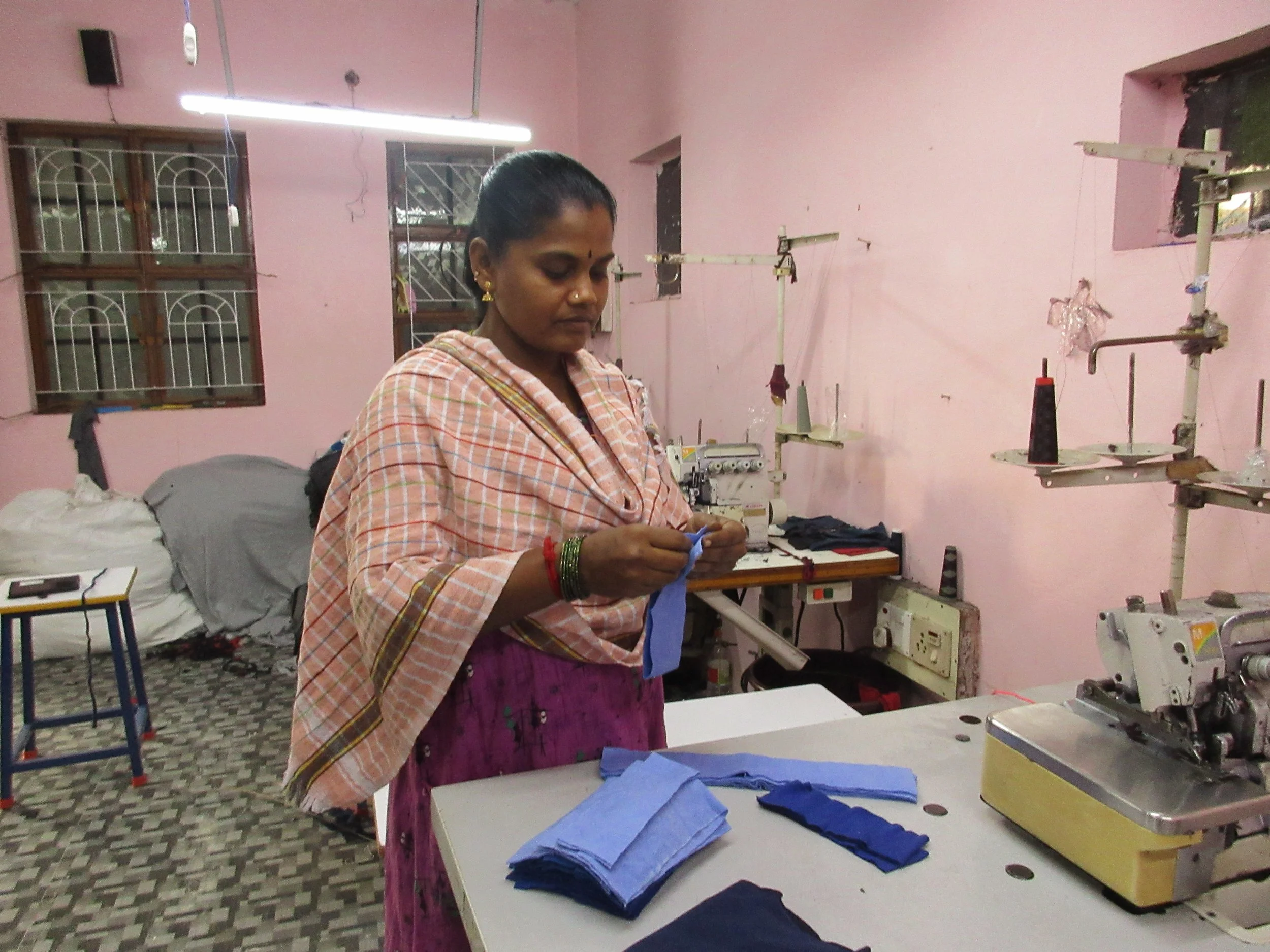 “When I shot this photo, that morning, the helper had not showed to up to the stitching, so the woman pictured was having to do two jobs, This will slow her down, and mean she’s paid less overall. If the helper comes, she can do 200 pieces – if the h