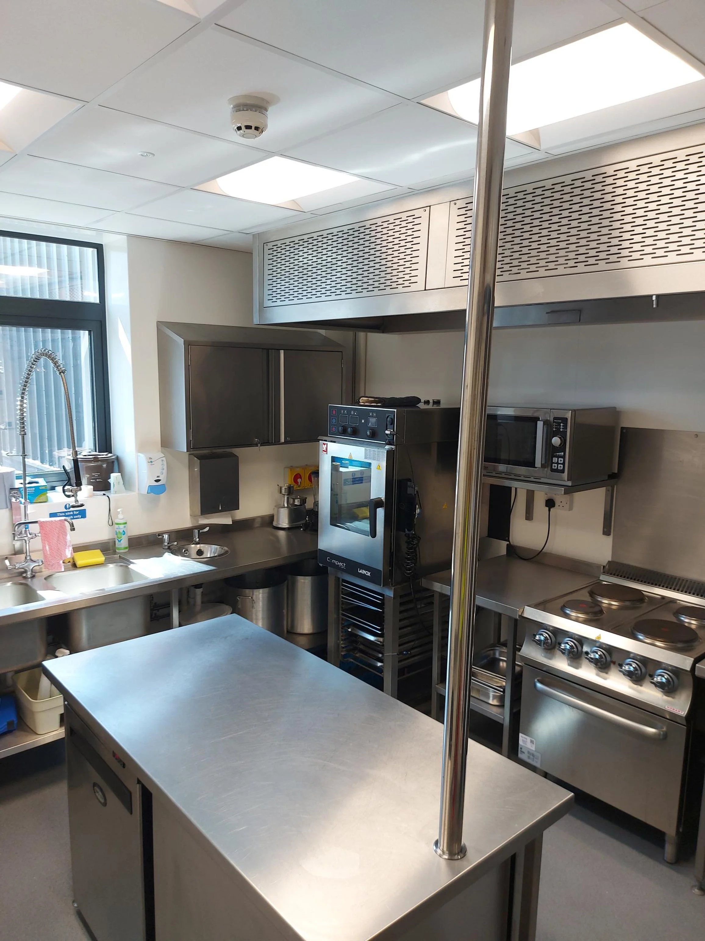 Commercial kitchen with stainless steel appliances, countertop, window, and cooking equipment.