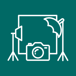 Photo studio setup with a backdrop, camera, umbrella lighting, and reflector.