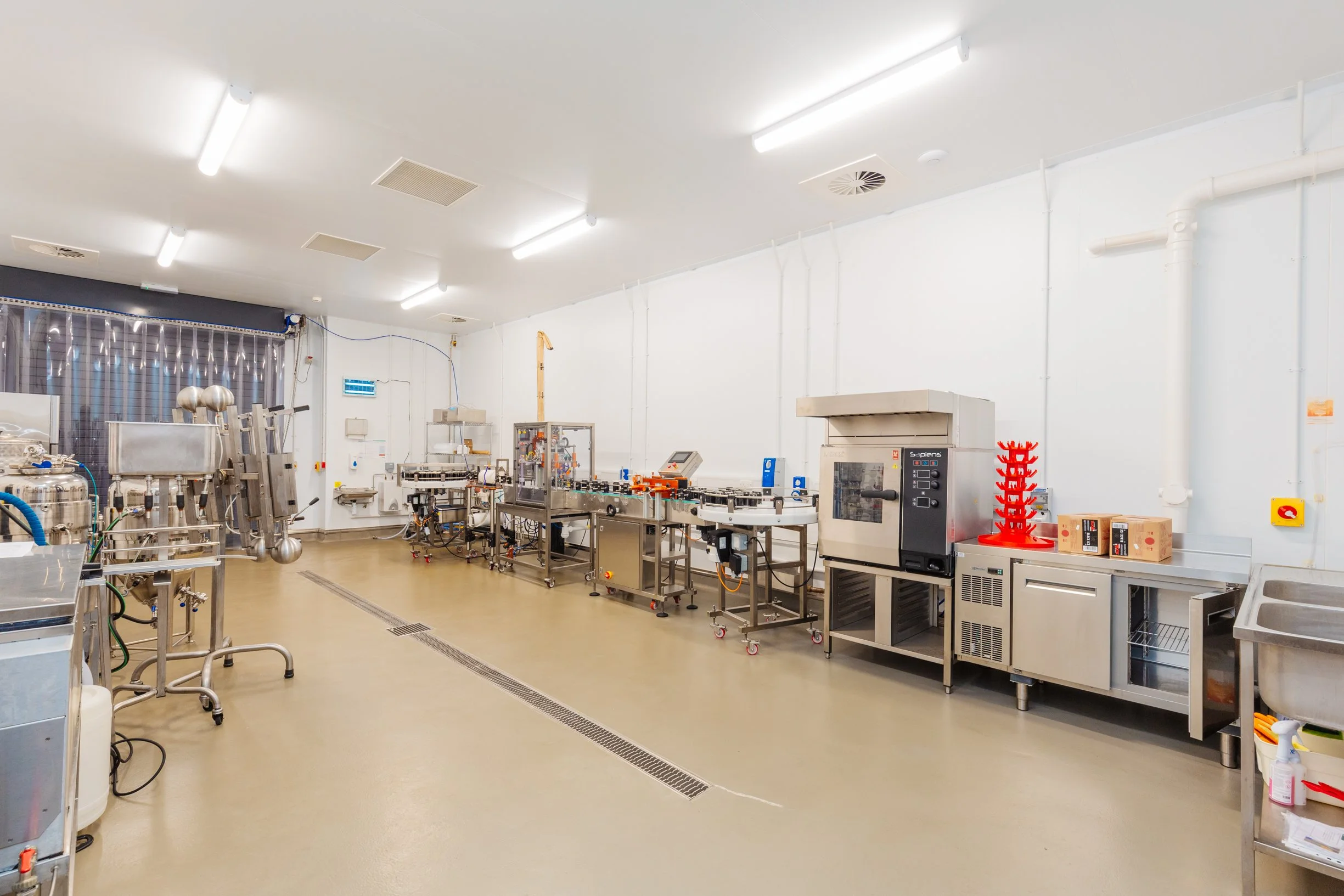 Drinks and dairy production equipment and a person in a white coat and hairnet (PPE)
