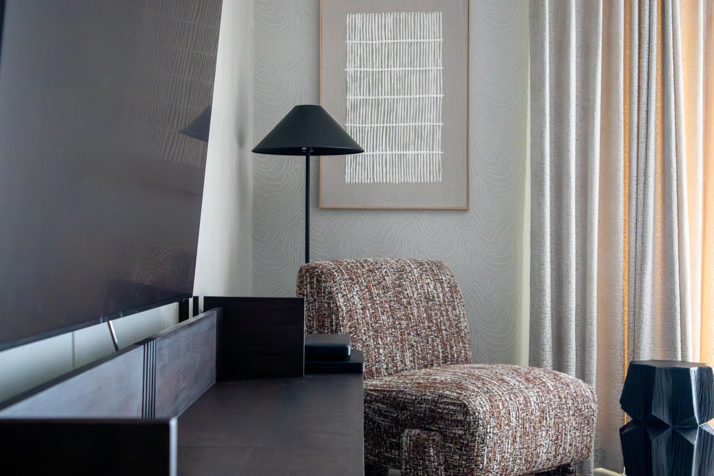 Textured armchair and soft lighting in Cambridge Water Lane living room with abstract art and sculptural side table.