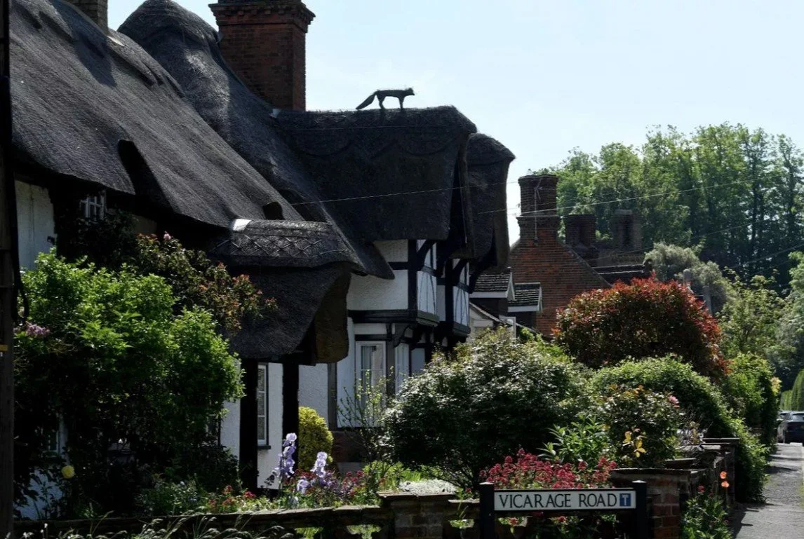 Thatched-roof cottages on Vicarage Road, Waresley, Cambridgeshire, with a straw fox on the roof.