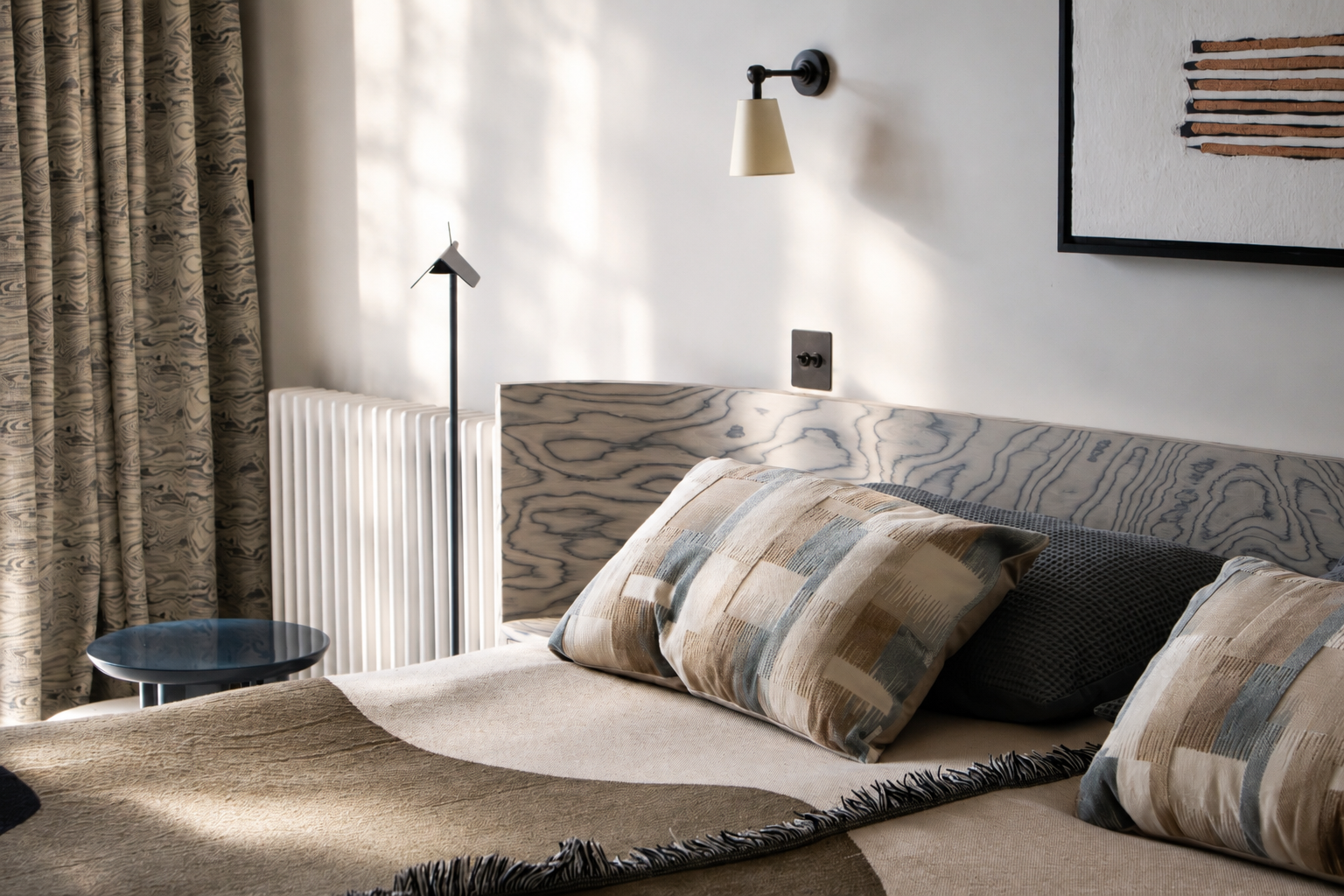 Bedroom in a Cambridge Water Lane new‑build renovation, with a patterned headboard, neutral geometric textiles, and a calm contemporary palette.