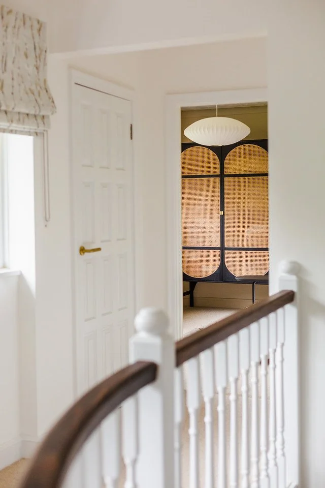 Japandi hallway detail from the Gamlingay renovation, showing rattan screen, white pendant light, and minimalist architecture.