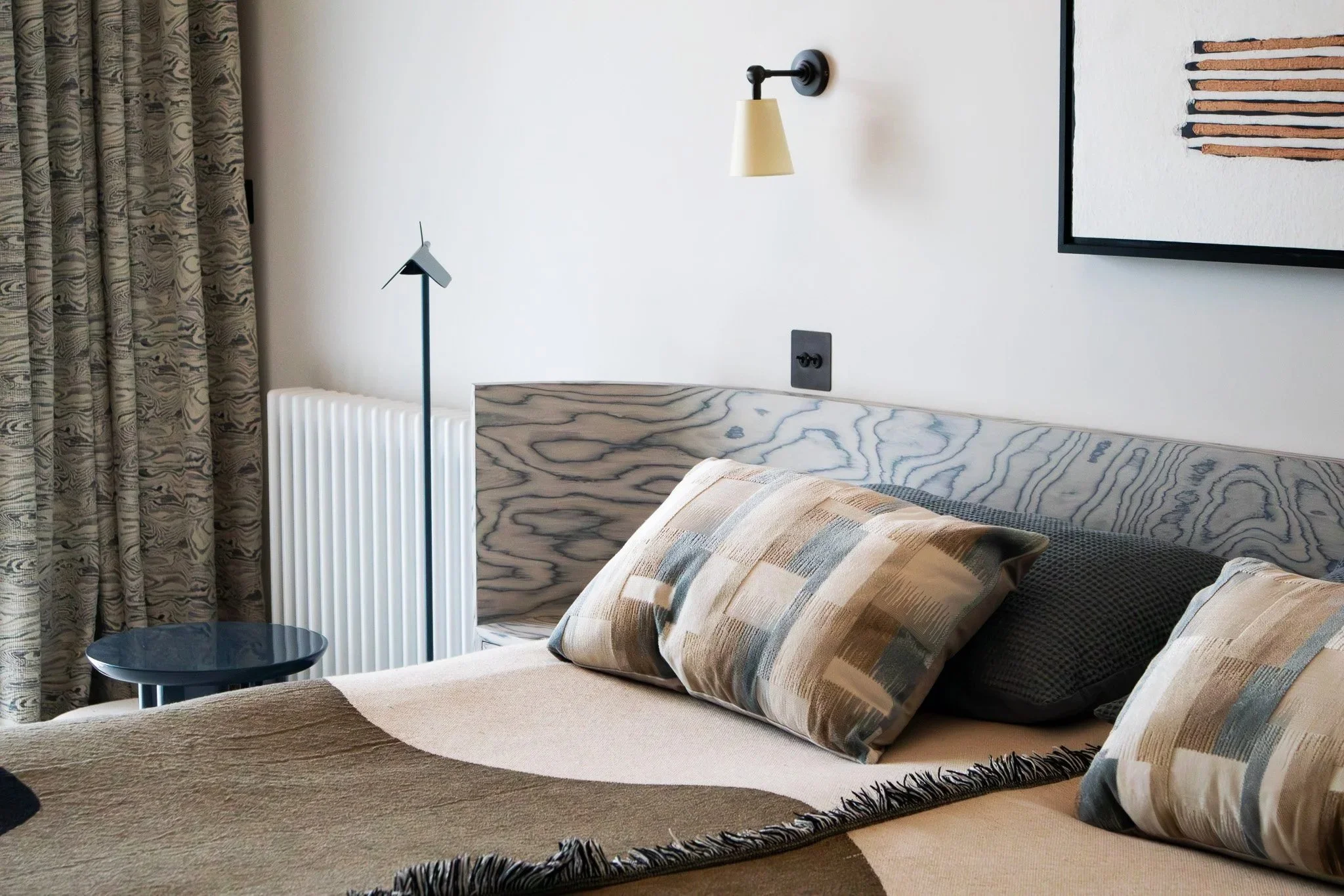 Bedroom in a Cambridge Water Lane new‑build renovation, with a patterned headboard, neutral geometric textiles, and a calm contemporary palette.