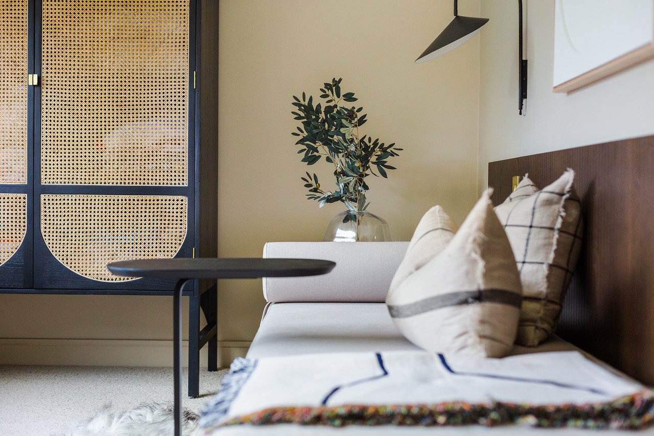 Japandi bedroom with rattan cabinet, sculptural lighting, and layered neutrals in Gamlingay renovation near Cambridge