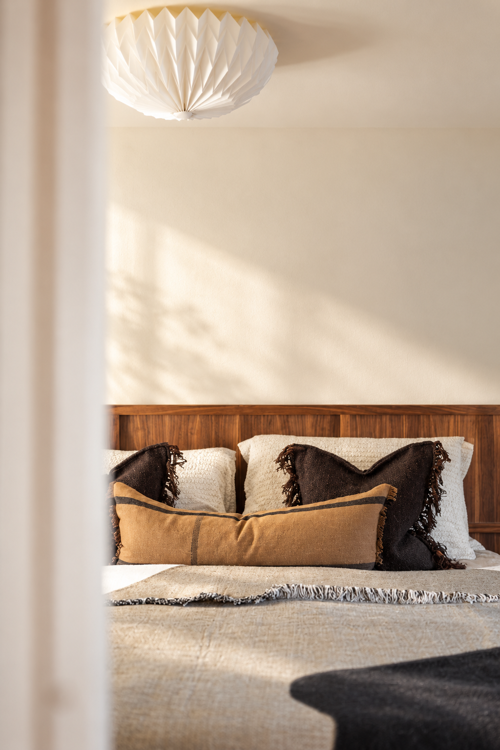 Warm neutral bedroom in a Grade II listed South Cambridgeshire renovation, with walnut headboard, layered textiles and soft natural light.