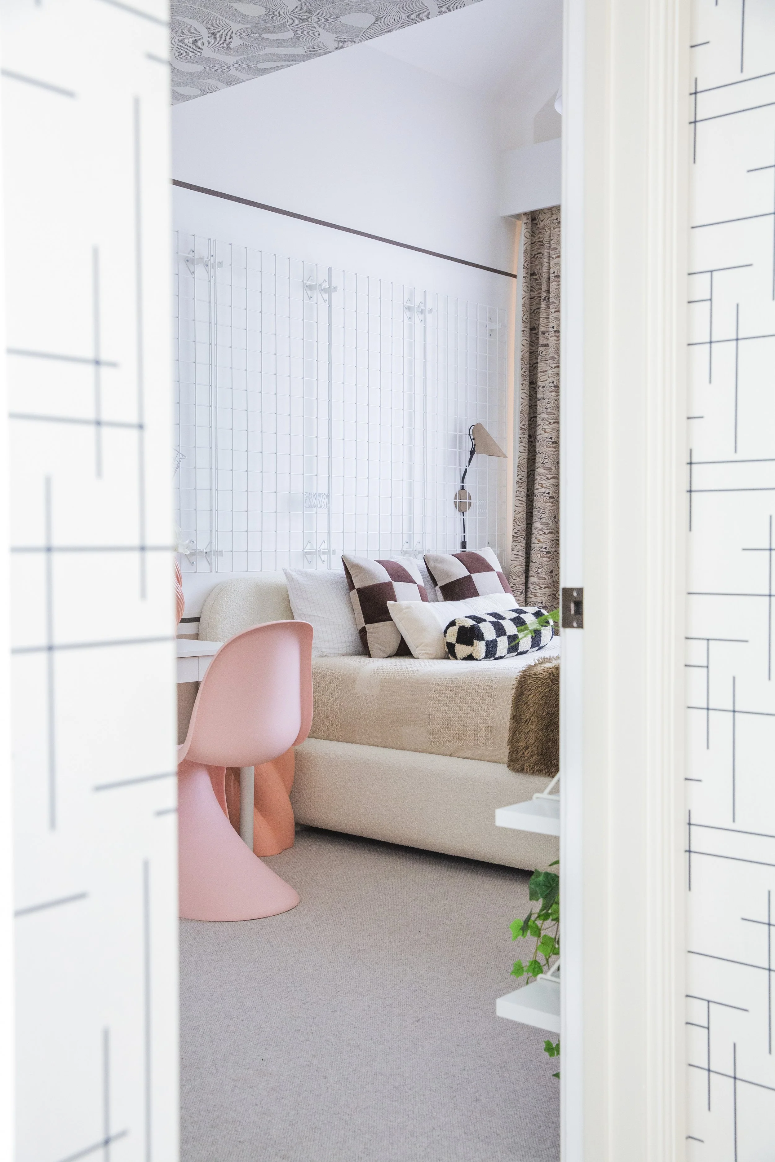 Scandinavian teen bedroom with beige bedding, patterned pillows, pink chair, and minimalist wall styling — Cambridge Water Lane.