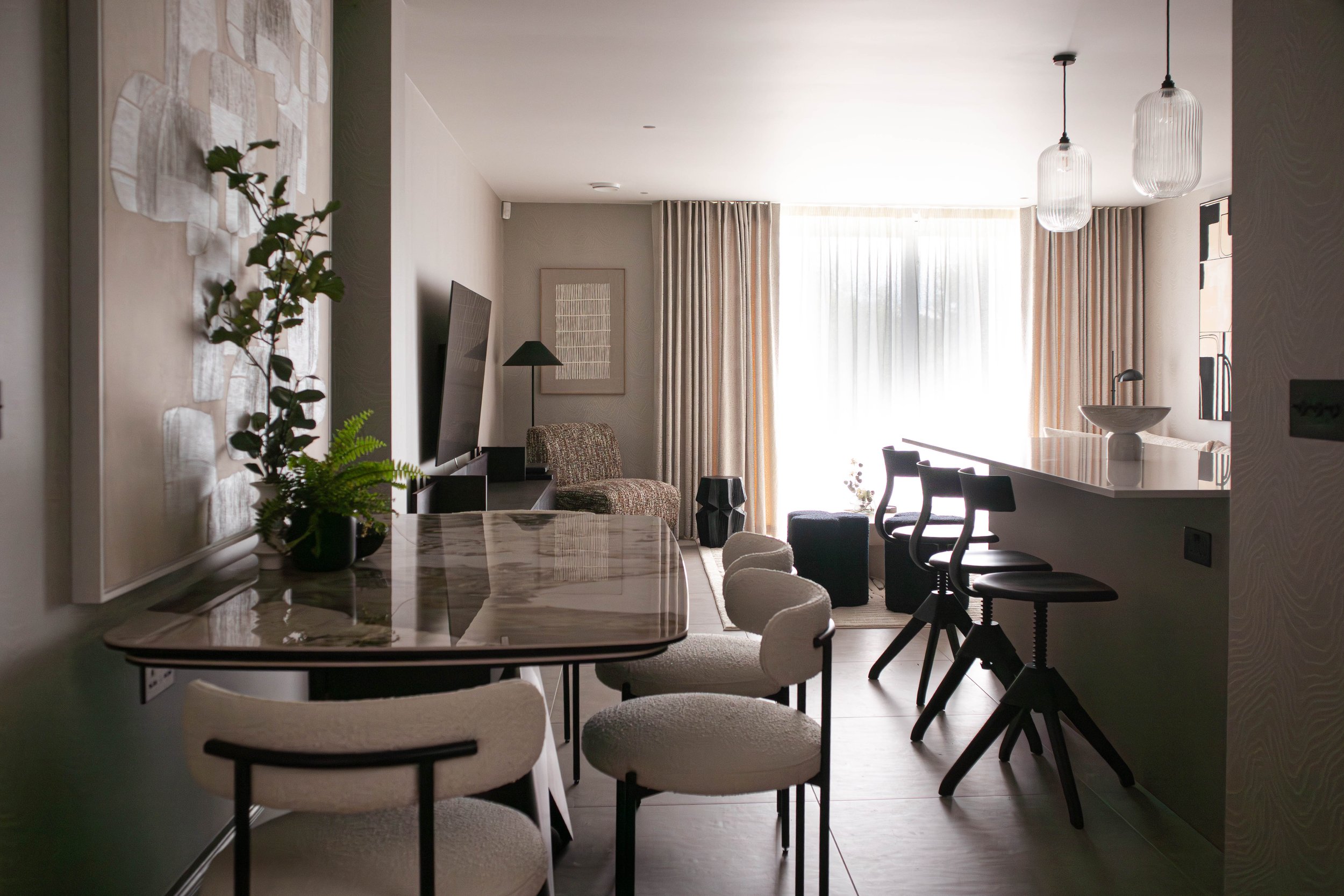 Wider view of the Water Lane living–dining space, showing the marble dining table, the bespoke sideboard, and the sculptural pendant light that anchors the open-plan layout