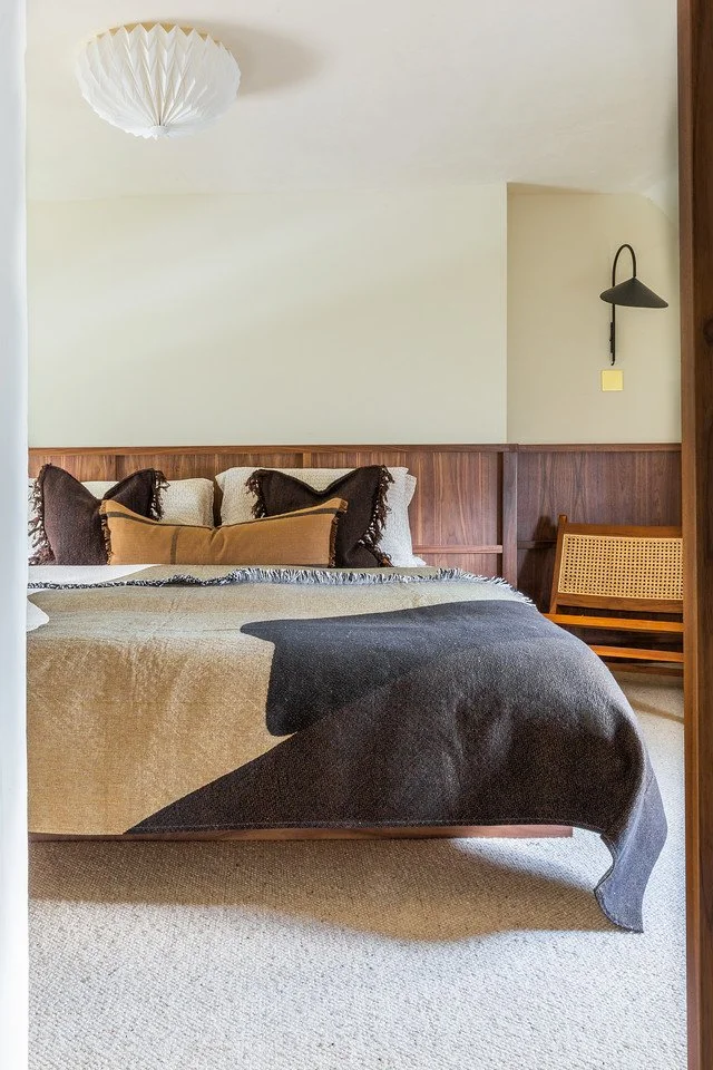 Grade II listed bedroom in South Cambridgeshire with modern lighting, abstract textiles, and natural materials.