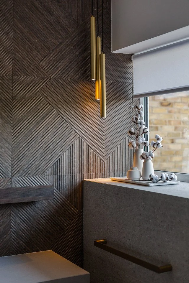 Modern bathroom corner with brass pendant lights, textured geometric wall, and soft accent mood lighting in a Gamlingay family home
