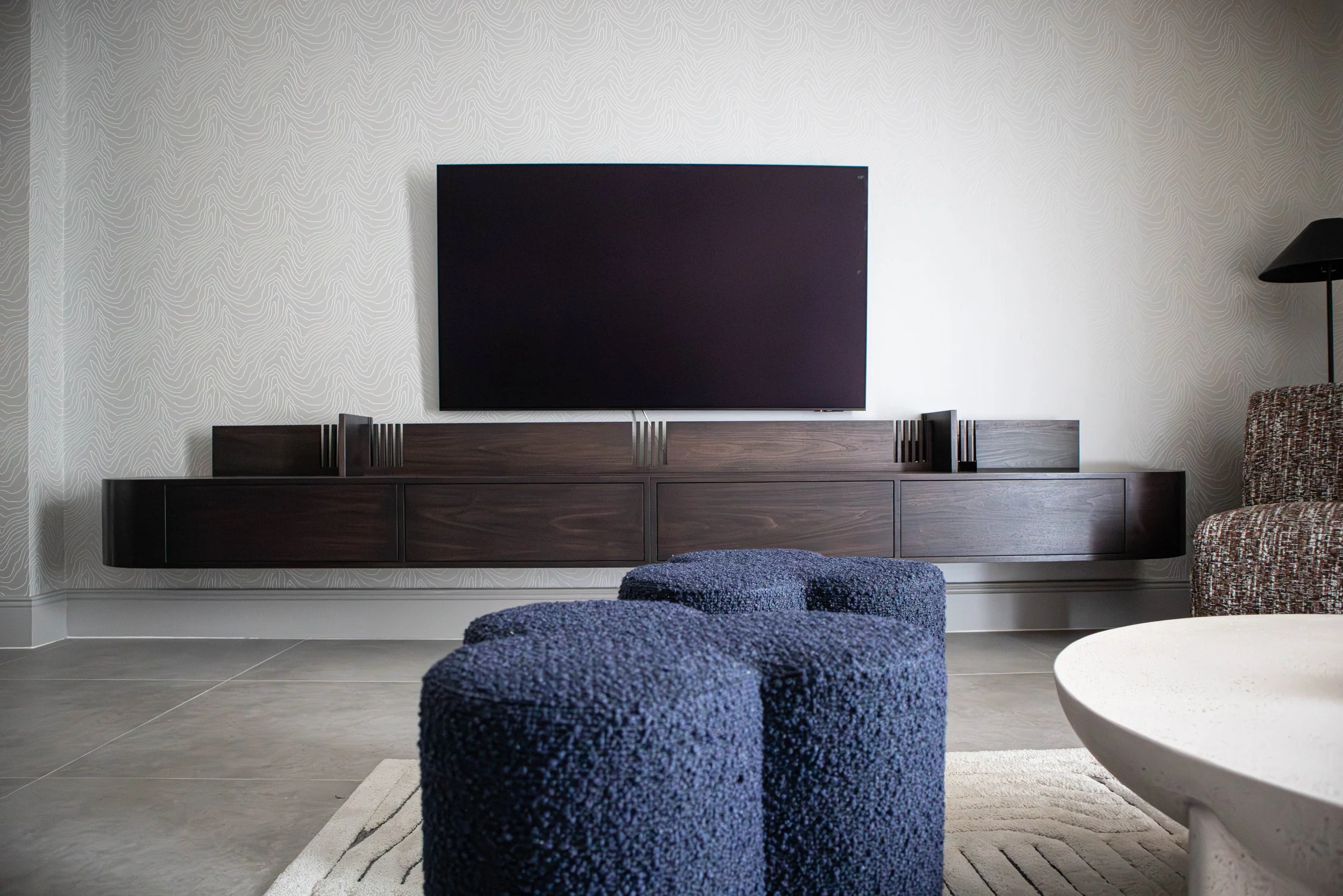 Front view of the bespoke media sideboard in the Water Lane living space, paired with sculptural blue stools and set against the project’s soft, textured palette