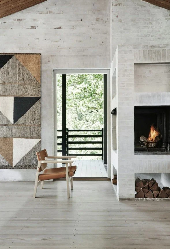 Nordic-style interior with vaulted timber ceiling, whitewashed brick walls, and a modern fireplace.