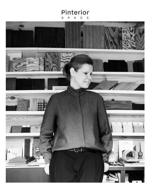 Interior designer standing in front of a materials wall — wood, texture, and colour samples in a Cambridge studio.