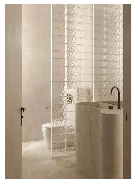 Zurich bathroom with matte plaster walls, sculptural stone basin, and glass tile partition.