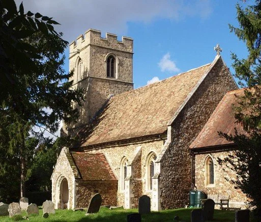 St Michael and All Angels Church in Caldecote, Cambridgeshire, with flint stone tower and surrounding graveyard.
