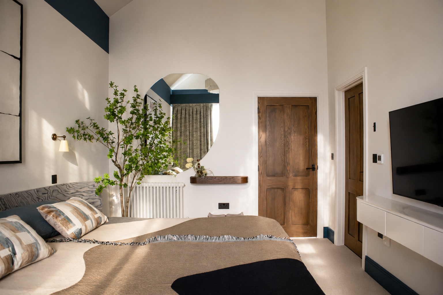 Bedroom in a Cambridge Water Lane new‑build renovation, featuring a bespoke mirror and custom-designed headboard, layered with neutral textiles and warm natural accents