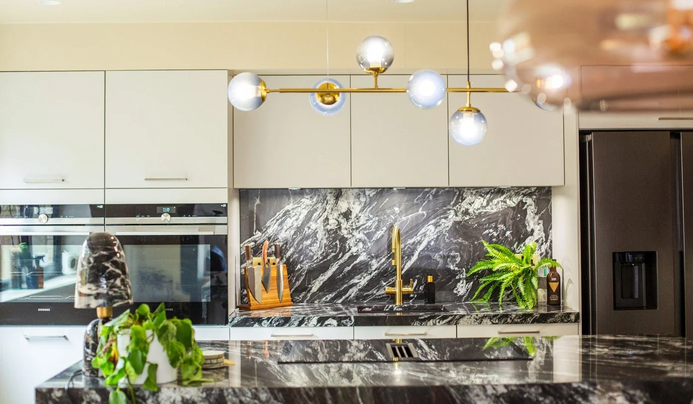 Modern kitchen interior featuring black and white marble surfaces, gold chandelier, and Siemens appliances — a refined blend of luxury and functionality in a period home renovation.