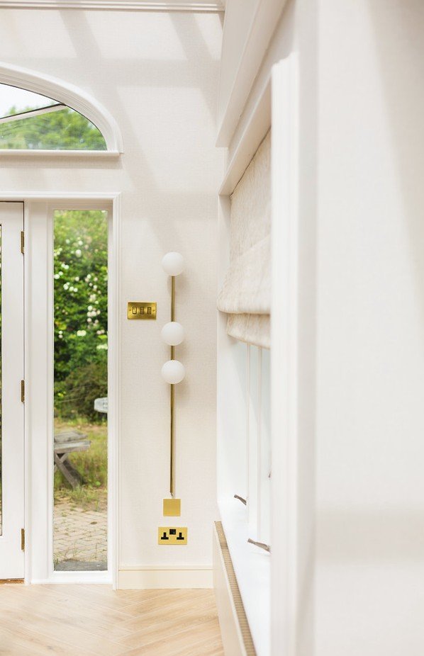 Brass lighting and natural textures in a Gamlingay dining room, where soft transitions and abundant daylight reflect the designer’s regional sensitivity and calm interior style
