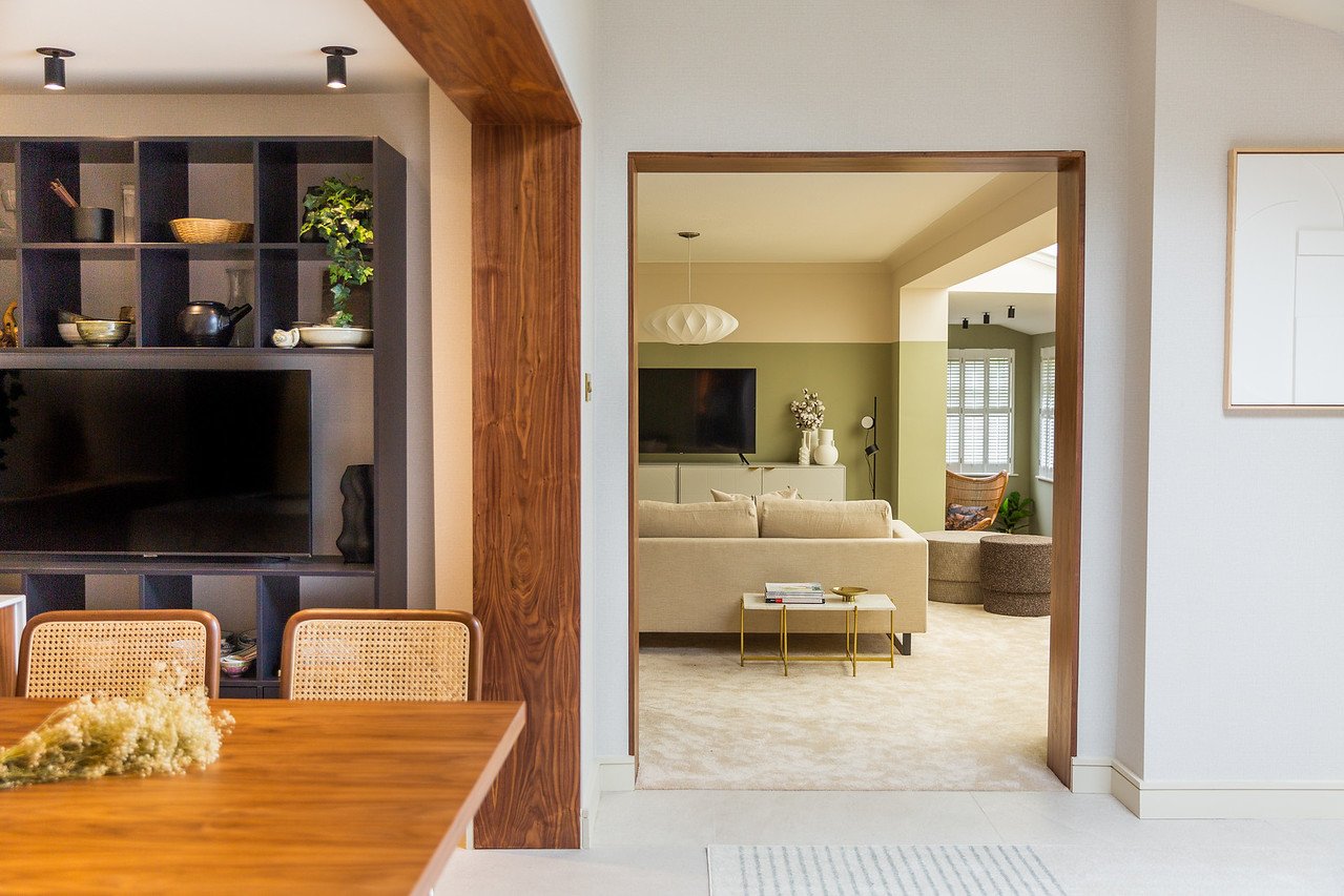 Open‑plan Gamlingay home showing a redesigned kitchen–dining–living flow, with warm materials, framed openings, and a cohesive palette that resolves a layout with four entry points