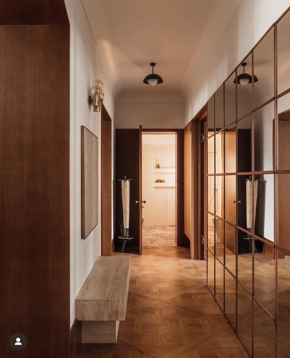 A narrow modern hallway with warm wood flooring, mirrored wall panels, a stone bench and soft ambient lighting, used as an example of small‑space design for Cambridge homes.
