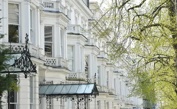 Victorian stucco townhouses in Holland Park, London, featuring decorative cornices, tall sash windows and a leafy residential streetscape.