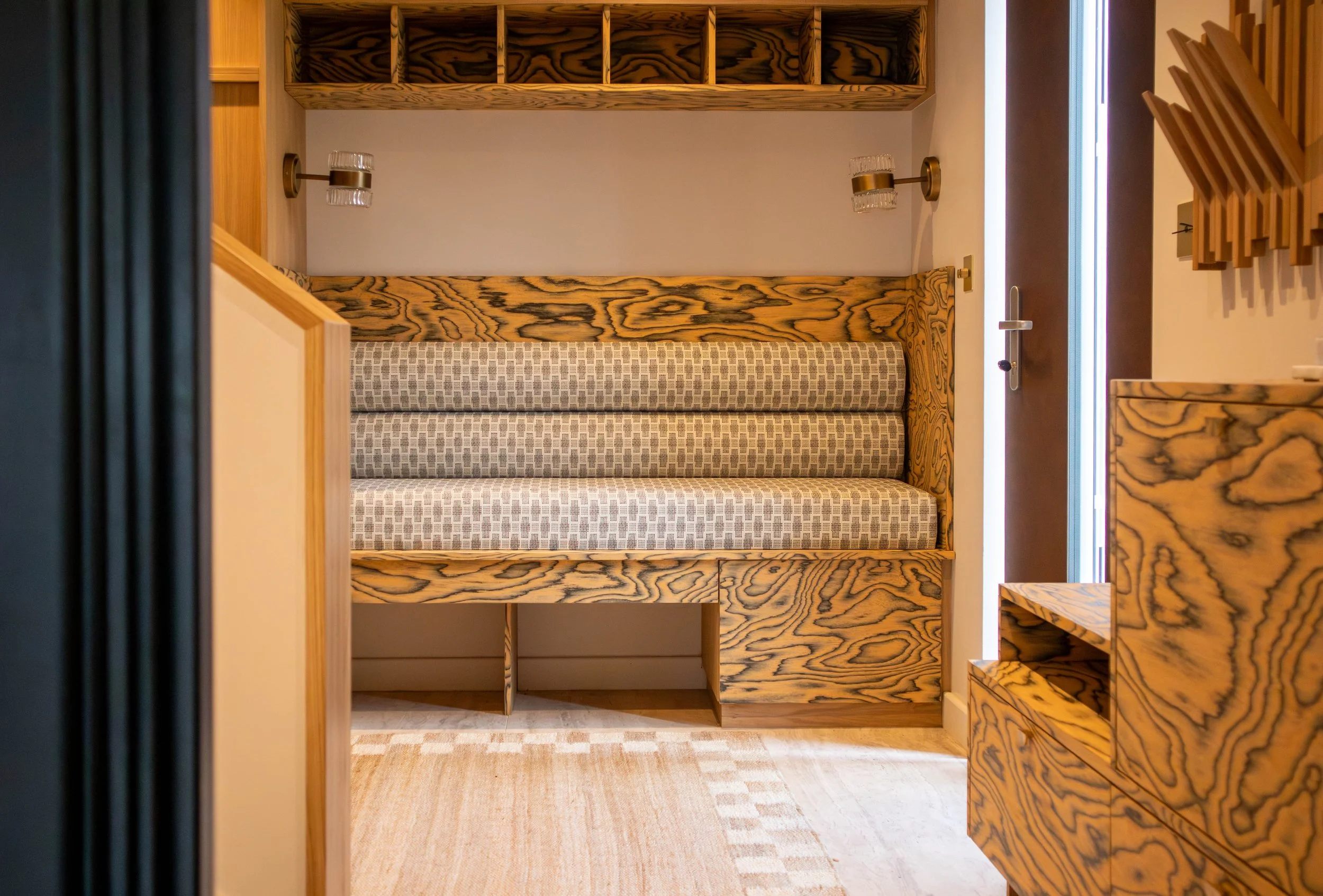 SBID award‑winning under‑stairs seating and hidden storage in the Shelford project, featuring bespoke timber joinery, integrated lighting, and sculptural grain patterns