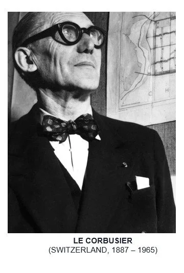 Black-and-white portrait of Le Corbusier wearing round glasses and a bow tie, with an architectural drawing pinned behind him