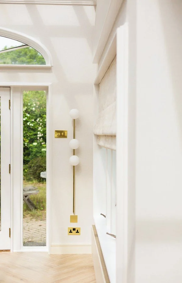 Vertical brass wall light with three globes shaping a bright, proportionally balanced interior.