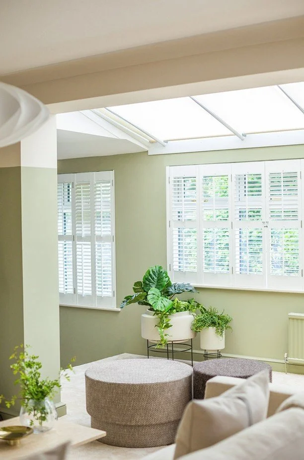 Cambridgeshire village interior with soft green walls, skylight, and Nordic-inspired natural textures.