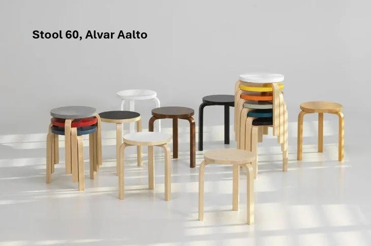 Collection of Alvar Aalto’s Stool 60 in various colours and wood finishes, arranged in a semi-circle with soft natural light.