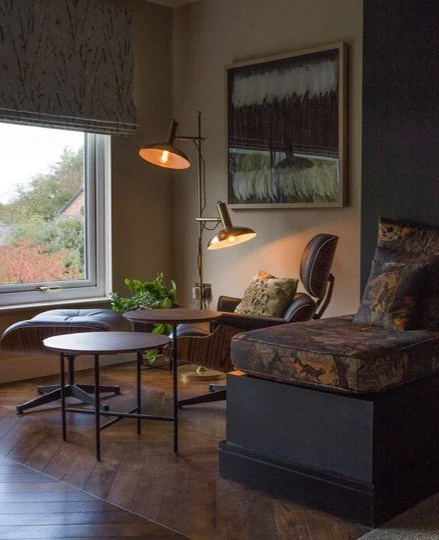 Reading nook in Gamlingay home with layered textures, warm lighting, and garden-facing Roman shade.