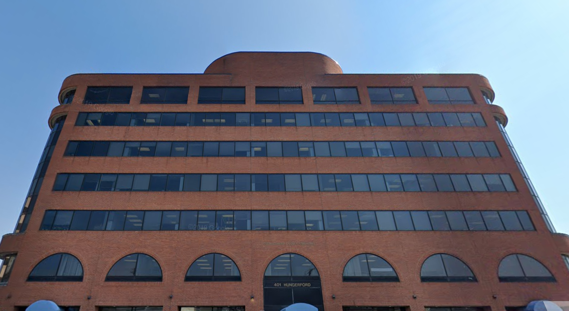A multi-story brick building with arched windows on the bottom floor and rectangular windows on the upper floors, with the address 401 Hungerford visible above the main entrance.