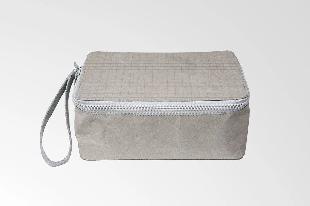 Gray fabric toiletry bag with zipper and wrist strap, grid pattern on top.