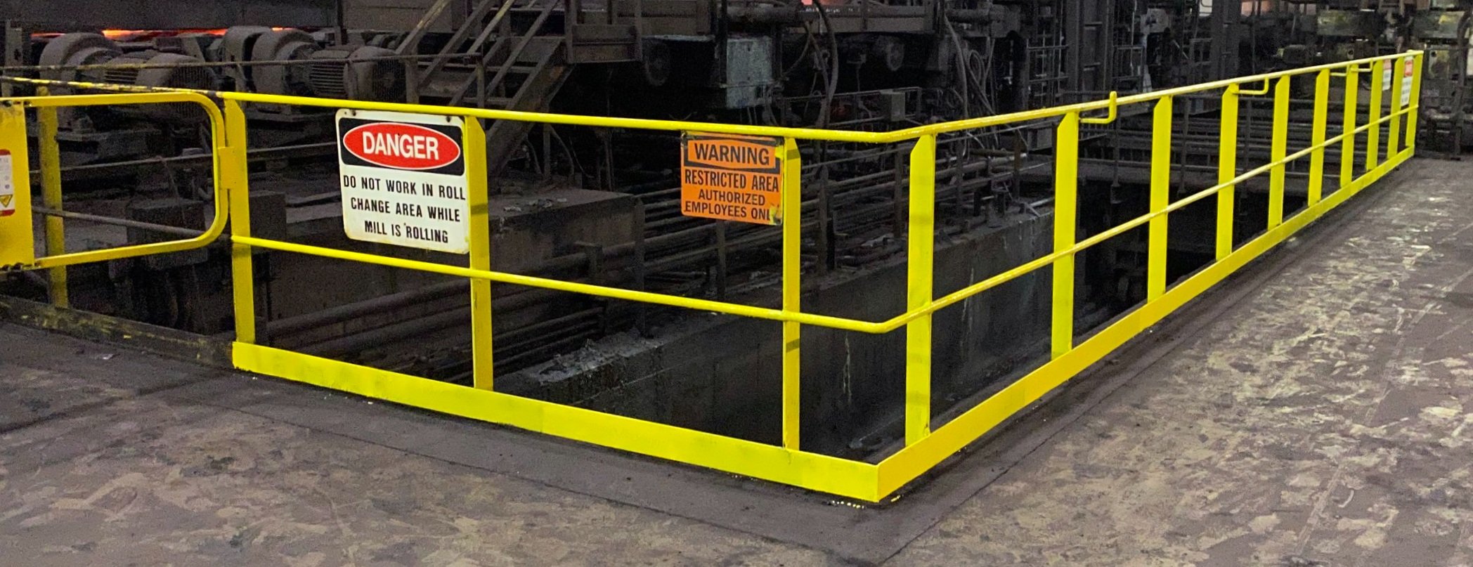 A painted yellow safety barrier surrounds a mill.