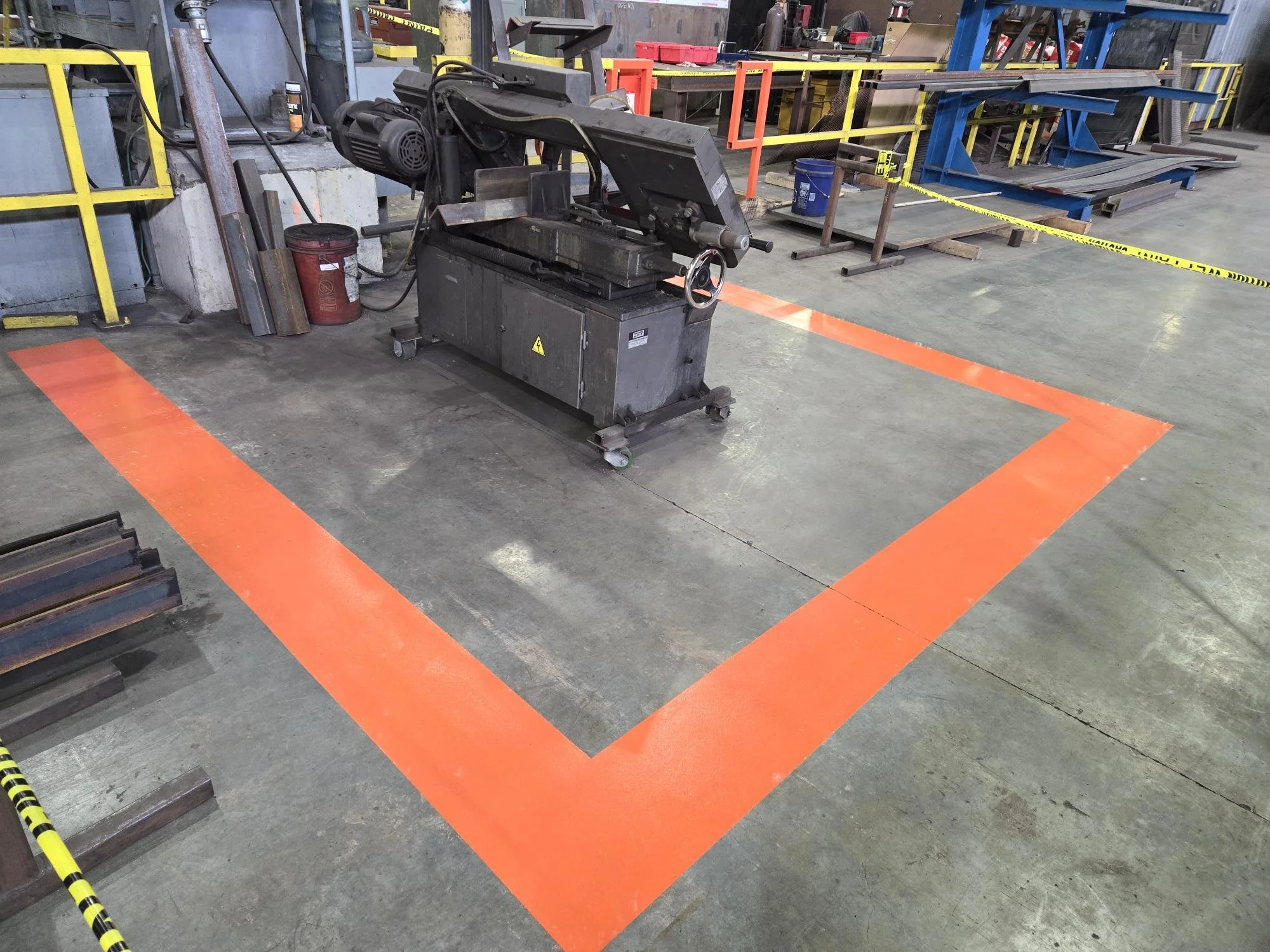 An industrial workspace with orange safety markings on the floor.
