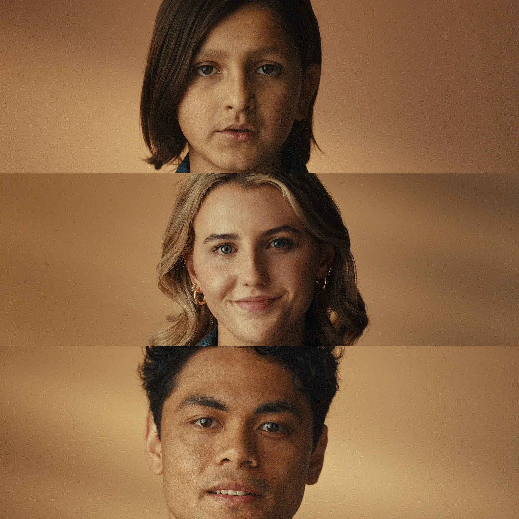 Close-up of three diverse young adults, with a woman in the middle smiling, a woman at the top with a serious expression, and a man at the bottom with a neutral expression, all against a blurred beige background.