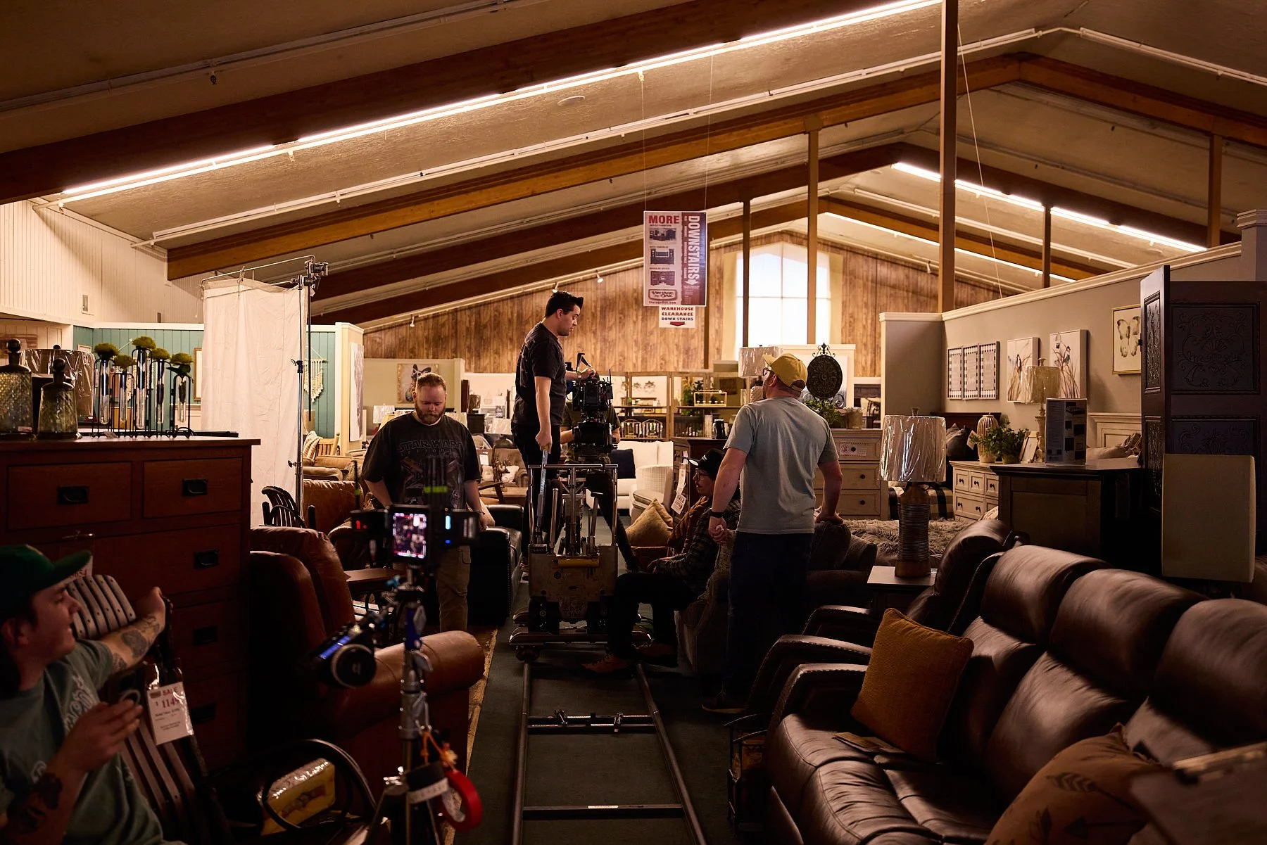 Filming crew working inside a furniture store, operating camera equipment and discussing a scene.