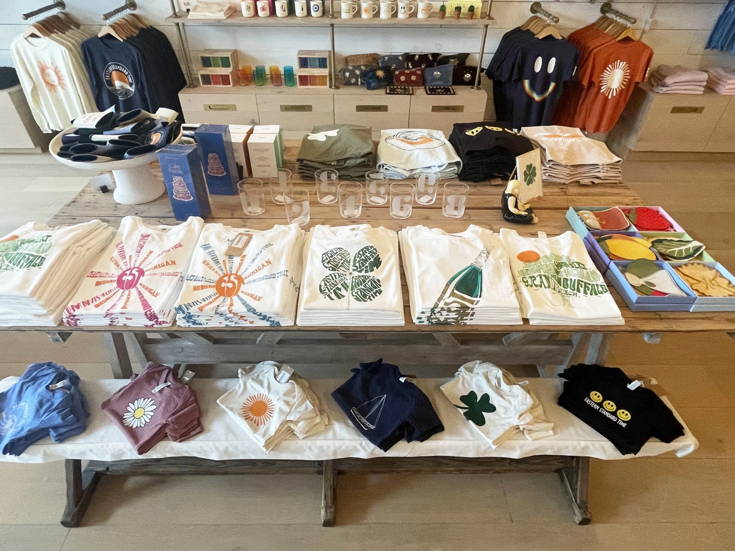 Display of graphic t-shirts with various designs and colors in a retail store, along with accessories and home decor items.