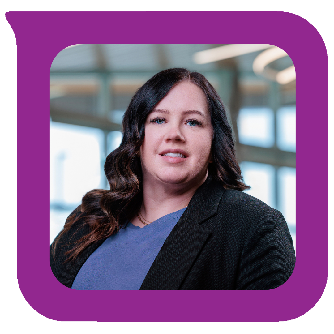 ပြတင်းပေါက်ကြီးတွေပါတဲ့ ခေတ်မီအဆောက်အအုံတစ်ခုမှာ ရပ်နေတဲ့ မှောင်မိုက်လှိုင်းတွန့်ဆံပင်နဲ့ အမျိုးသမီးတစ်ယောက်ရဲ့ ပုံတူ။ အနက်ရောင်ဘလေဇာအင်္ကျီနဲ့ အပြာရောင်အပေါ်အင်္ကျီကို ဝတ်ဆင်ထားတဲ့ပုံ။