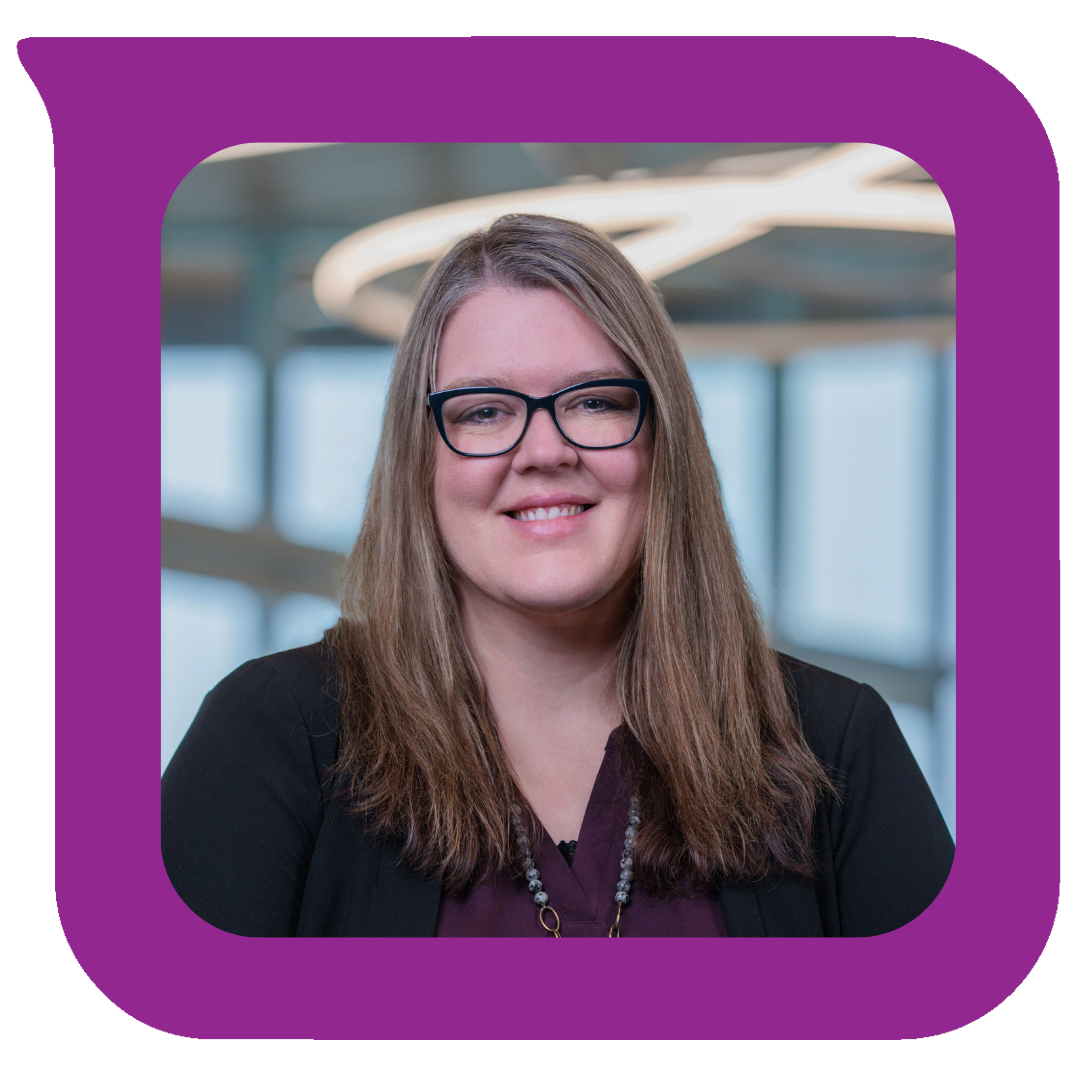 မျက်မှန်တပ်ထားပြီး အနက်ရောင်ဘလေဇာအင်္ကျီနှင့် ပုတီးလည်ဆွဲဝတ်ဆင်ထားသည့် အပြုံးပိုင်ရှင် အမျိုးသမီးတစ်ဦးသည် ပြတင်းပေါက်ကြီးများနှင့် နောက်ခံတွင် စက်ဝိုင်းပုံမီးအိမ်တစ်ခုပါရှိသော ခေတ်မီအိမ်တွင်းအလှဆင်မှုတွင် ရပ်နေသည်။