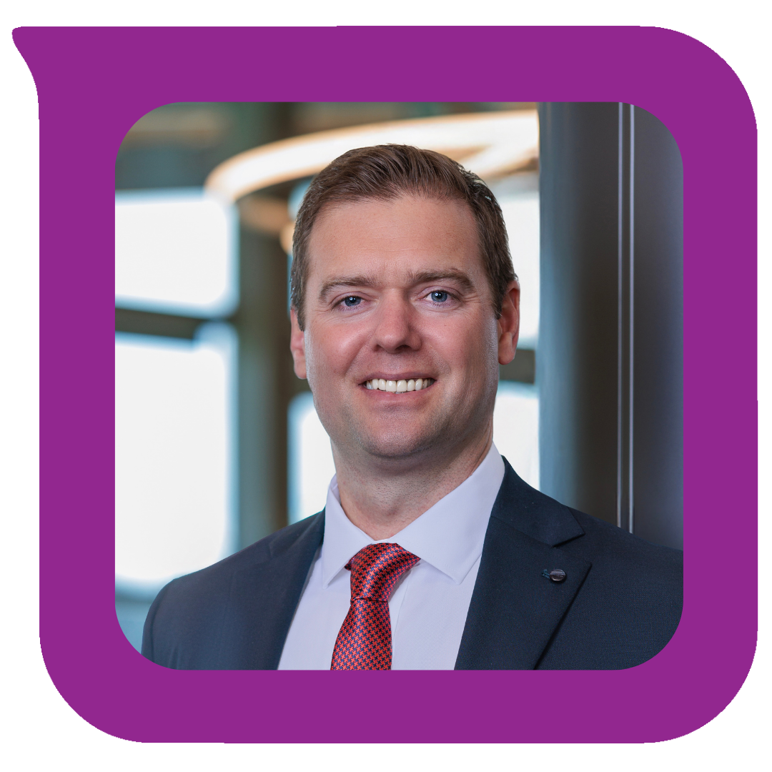 ရုံးခန်းပတ်ဝန်းကျင်တွင် ရပ်နေသော ဝတ်စုံနှင့် အနီရောင် နက်ကတိုင်ဝတ်ဆင်ထားသည့် ပြုံးရွှင်နေသော အမျိုးသားတစ်ဦး၏ ပရော်ဖက်ရှင်နယ် ဓာတ်ပုံ။