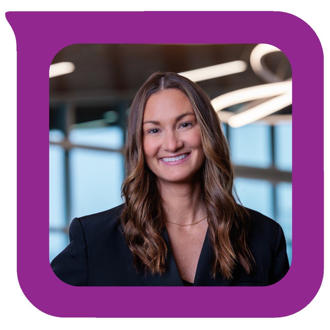 ခေတ်မီရုံးခန်းတစ်ခုထဲတွင် အနက်ရောင်ဘလေဇာအင်္ကျီဝတ်ဆင်ထားပြီး လှိုင်းတွန့်အညိုရောင်ဆံပင်နှင့် ပြုံးရွှင်နေသော အမျိုးသမီးတစ်ဦး။